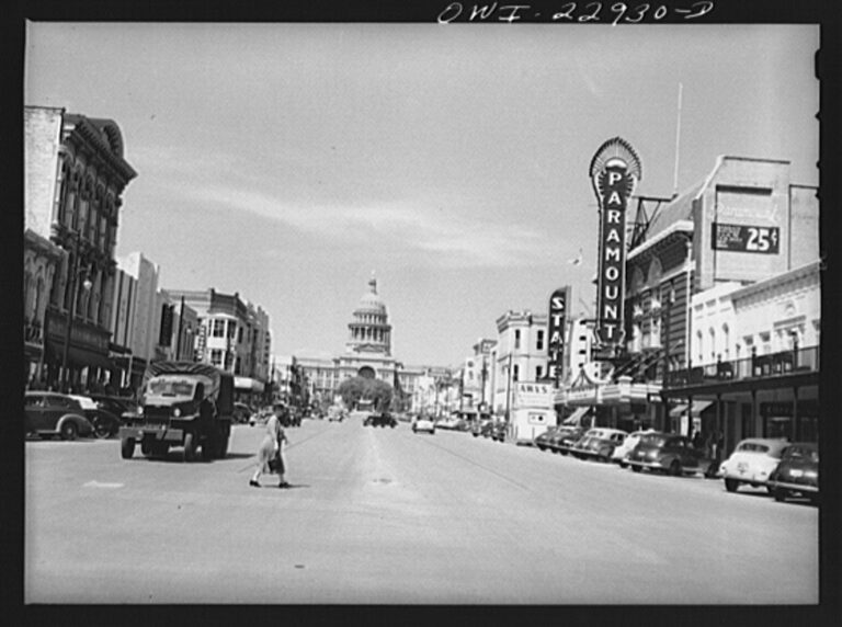 A 1943 black-and-white view up Congress Avenue to the Texas Capitol, with the Paramount and State theater signs on the right