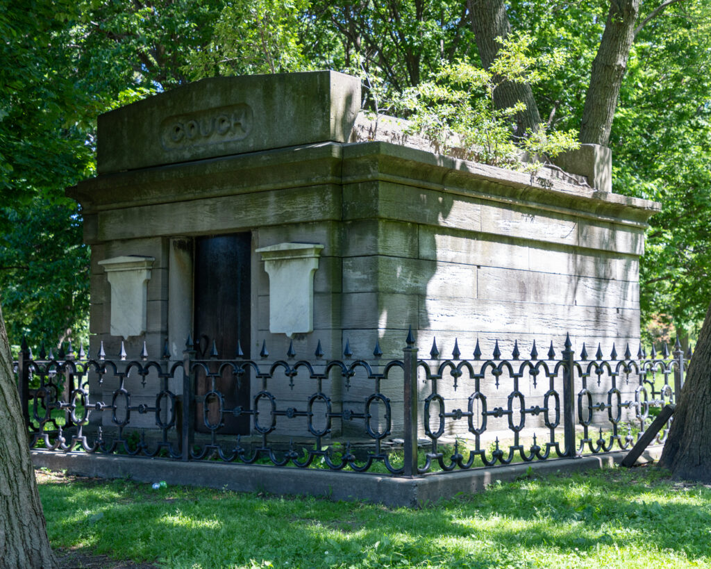 The Couch family tomb, a stone vault behind an iron fence among the trees of Lincoln Park