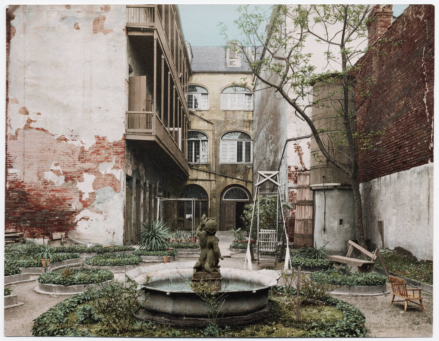 A tinted photo of a walled courtyard with a fountain, peeling plaster and wooden galleries