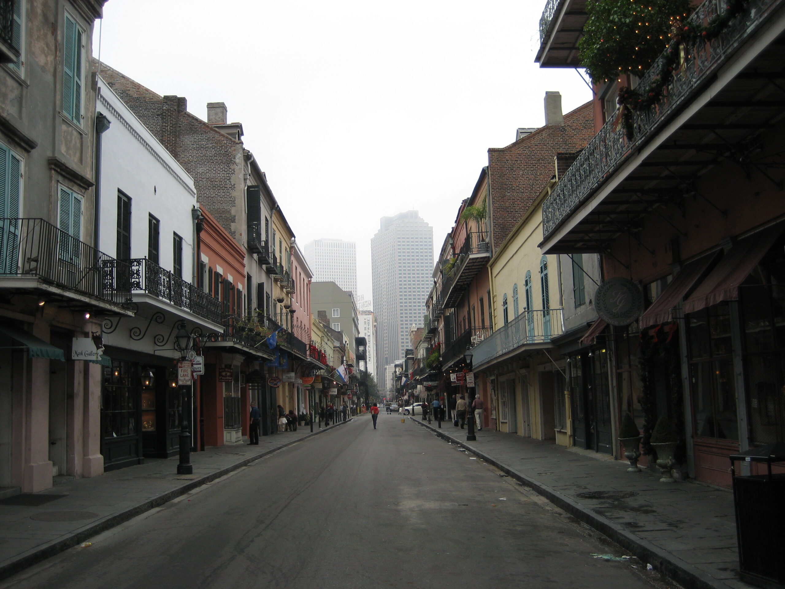 An empty French Quarter street with iron balconies, fading into fog and tall buildings