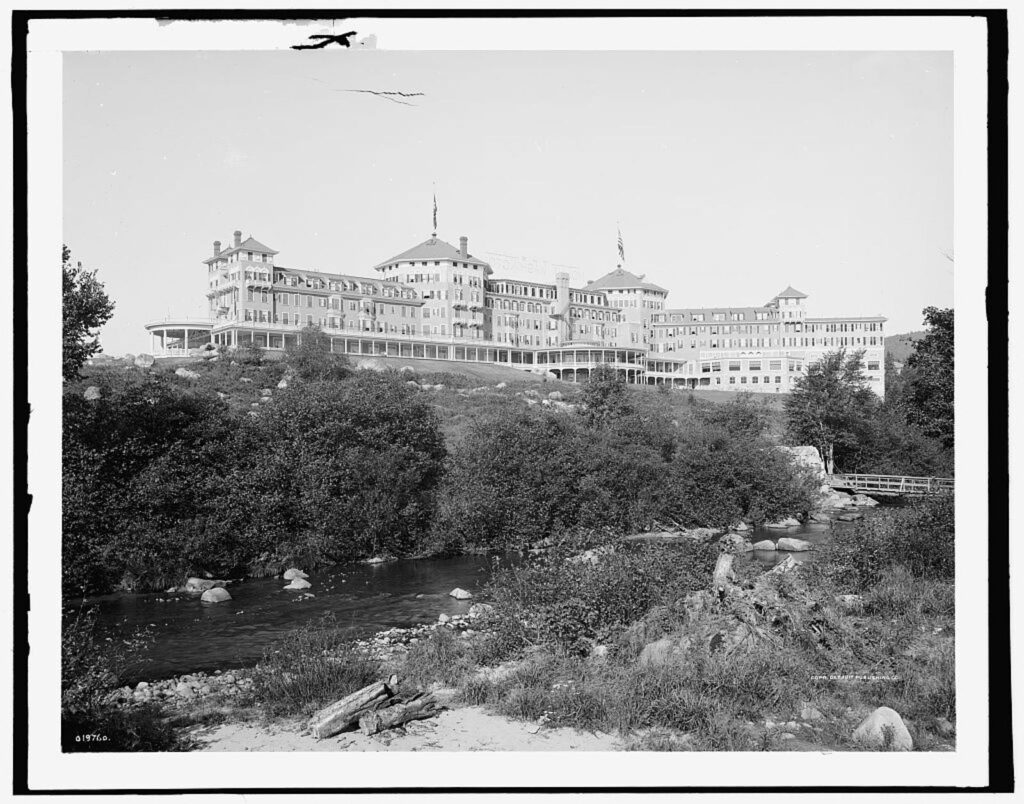 The hotel on a rise above a rocky stream, in a black-and-white photograph
