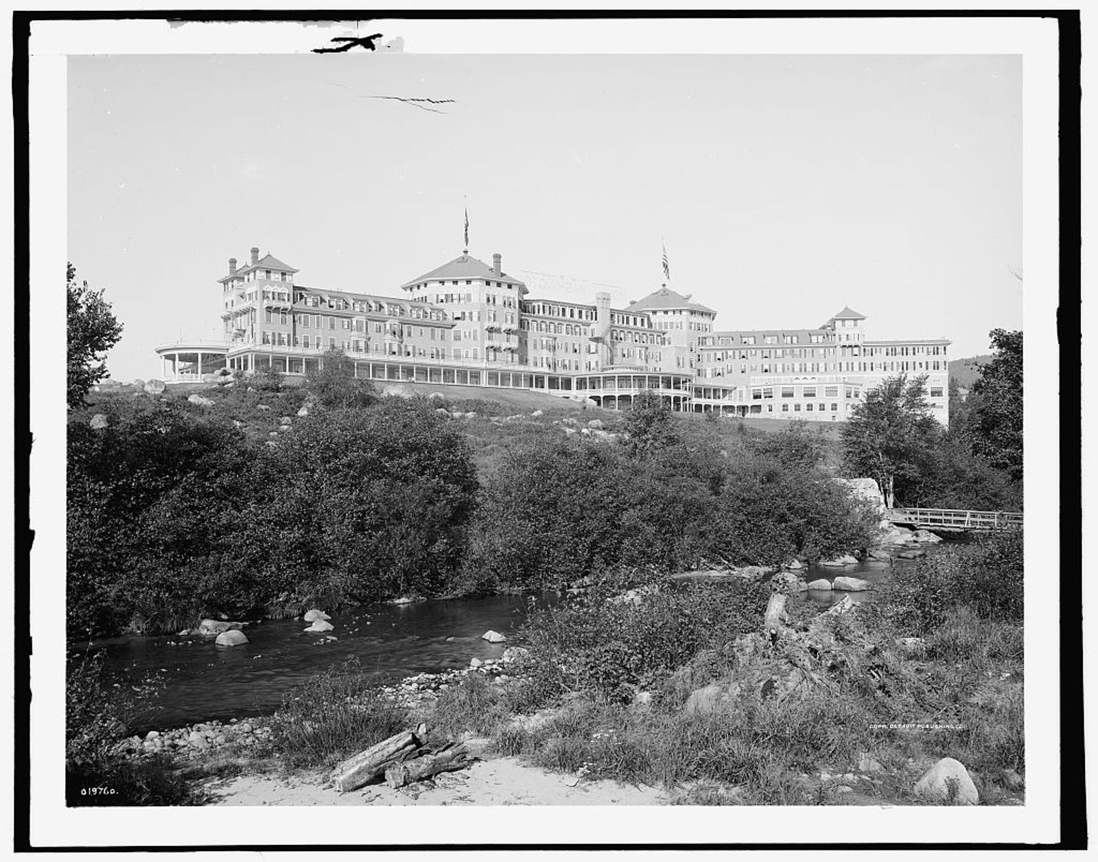 The hotel on a rise above a rocky stream, in a black-and-white photograph