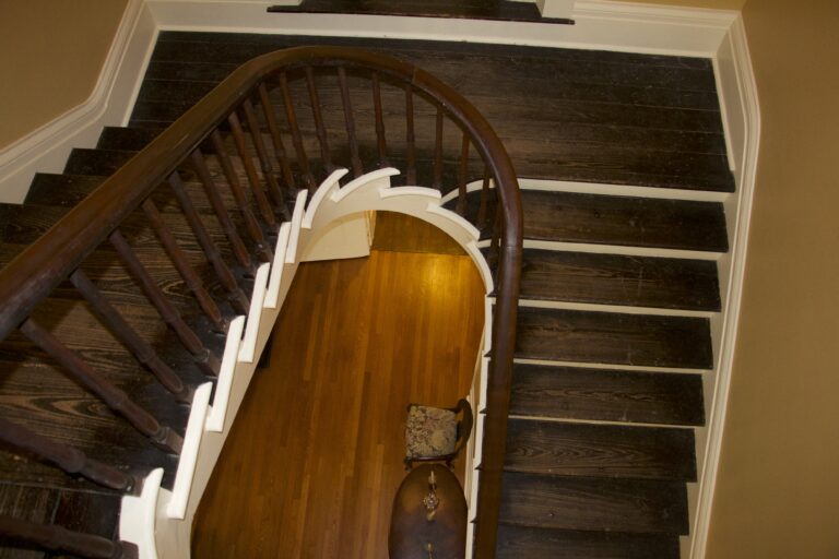 A curving wooden staircase seen from the top, its banister wrapping around a view of the floor below