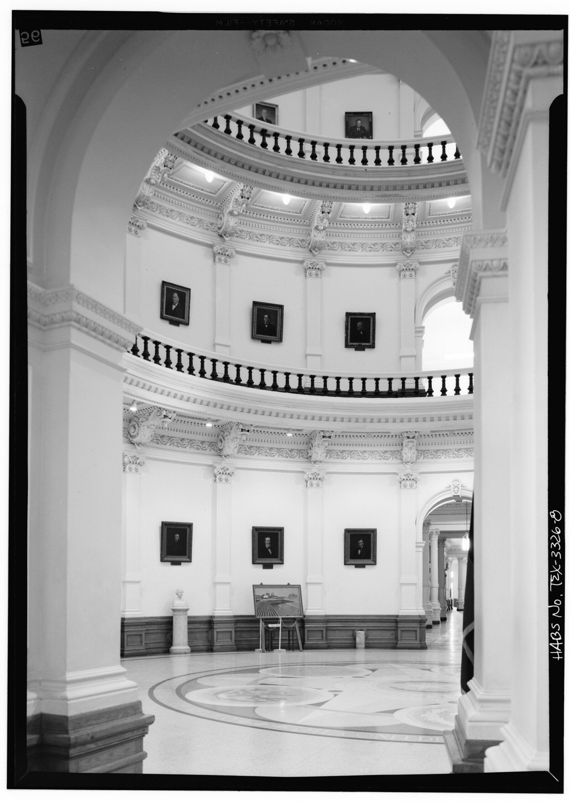 Black-and-white view up through the Texas Capitol Rotunda, with ringed balconies and rows of portraits on the curved walls