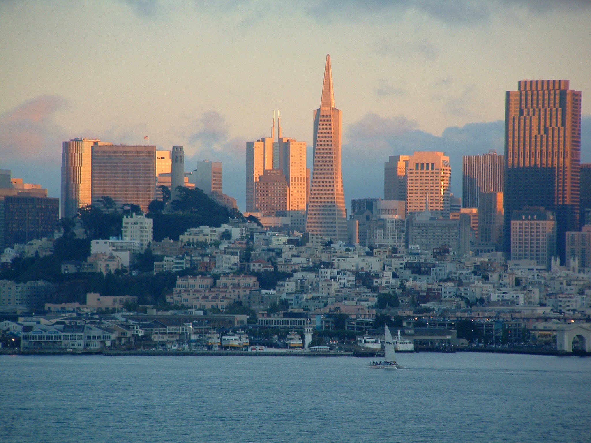 The downtown San Francisco skyline at sunset, seen across the water, with the Transamerica Pyramid at its center
