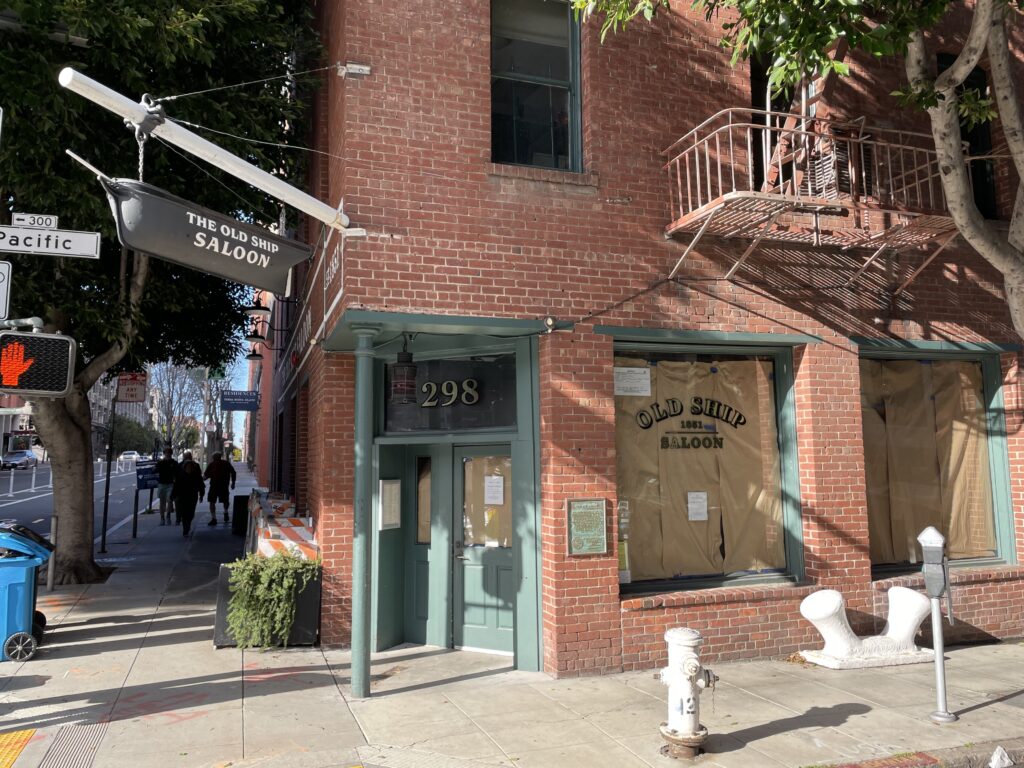 The brick corner entrance of the Old Ship Saloon at 298 Pacific Avenue, under its hanging ship sign