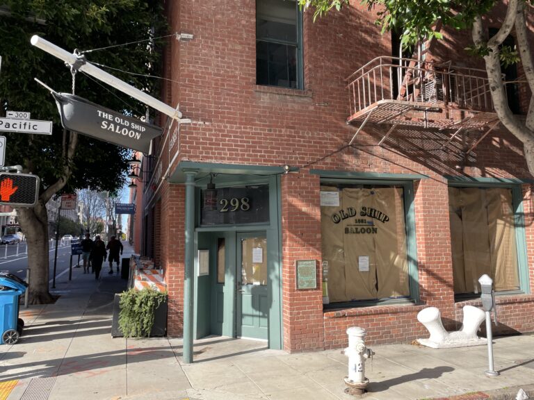 The brick corner entrance of the Old Ship Saloon at 298 Pacific Avenue, under its hanging ship sign