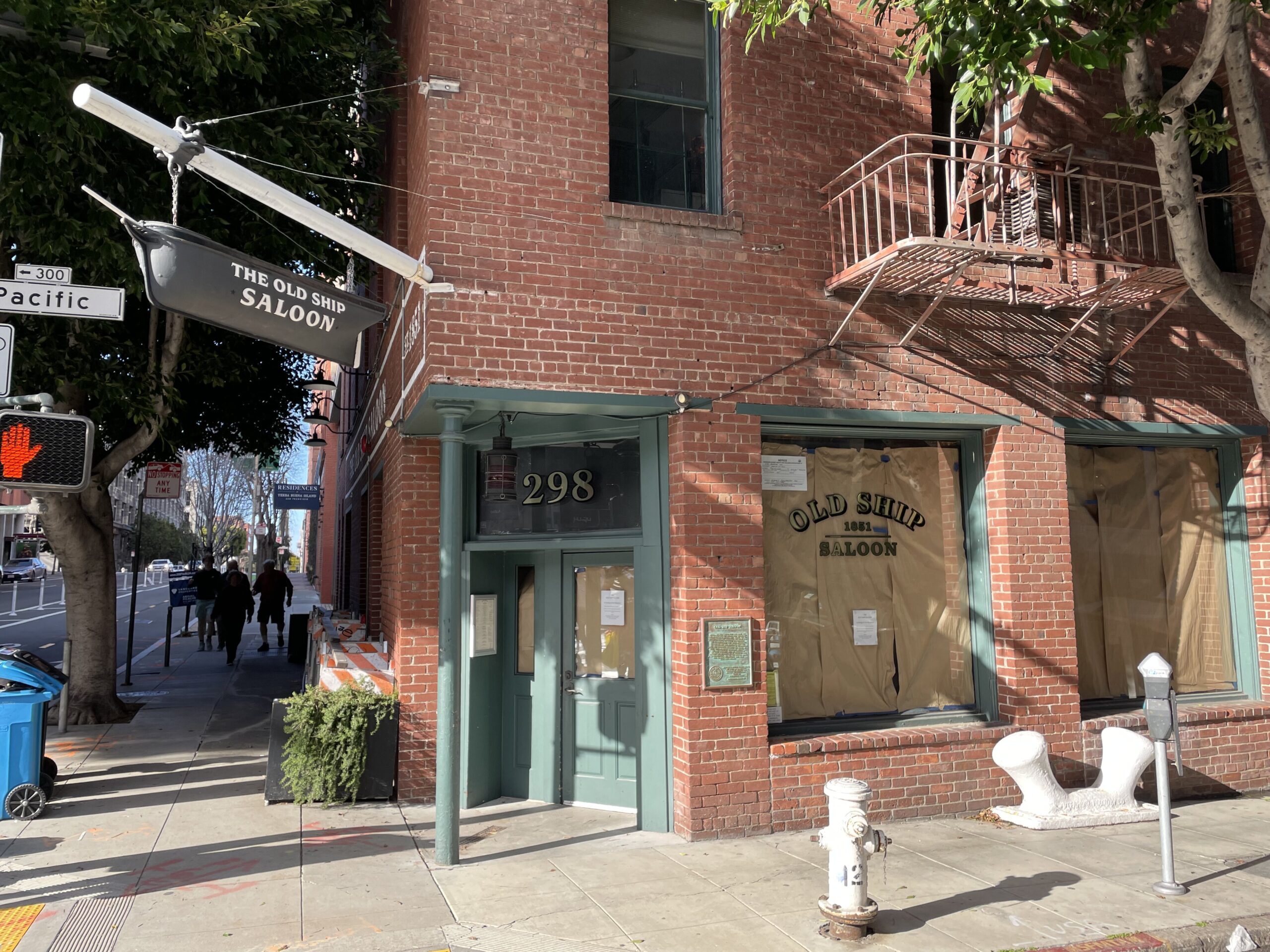 The brick corner entrance of the Old Ship Saloon at 298 Pacific Avenue, under its hanging ship sign