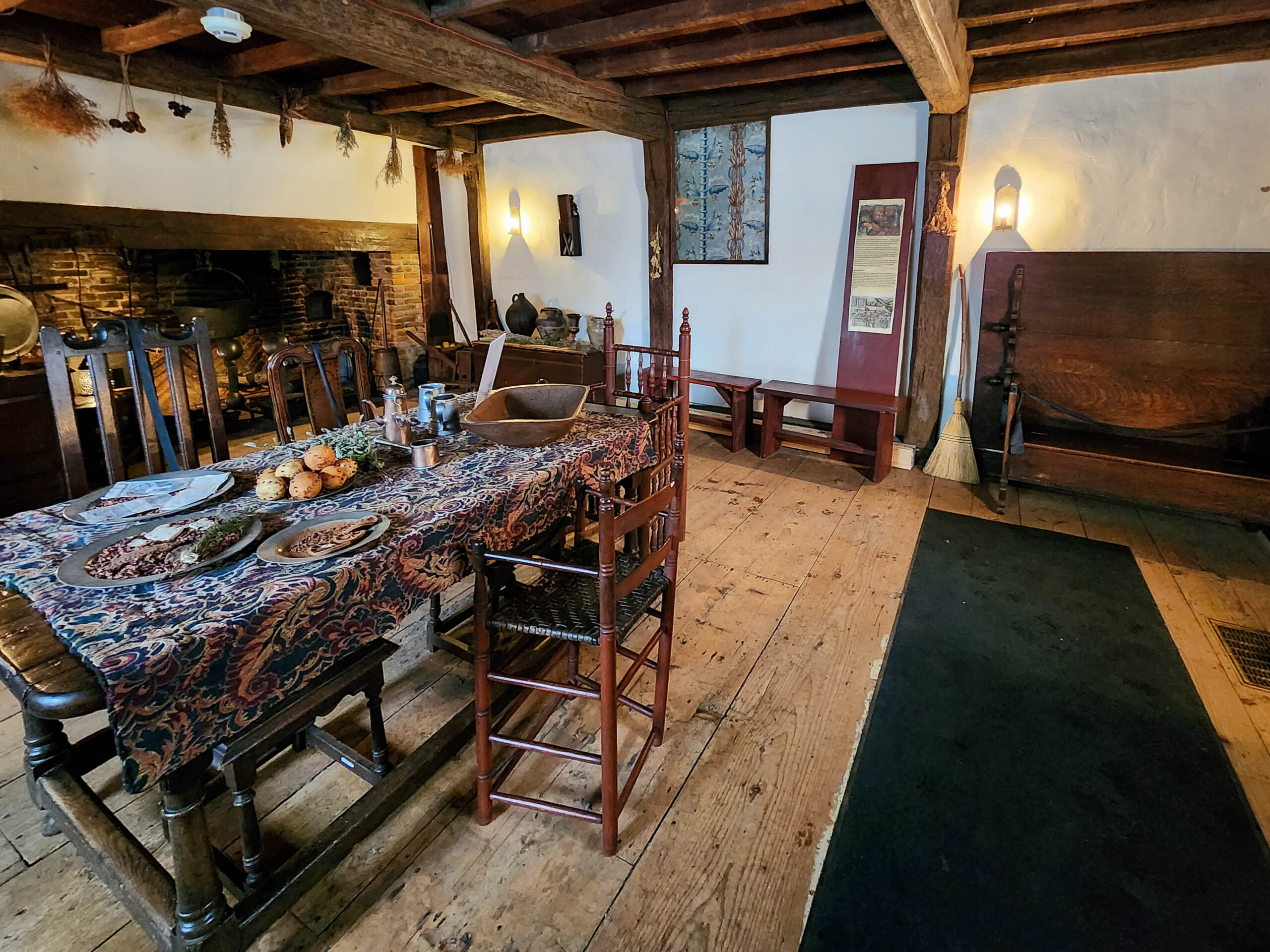 A bedchamber in the Witch House with a curtained bed, a period gown on a stand and a wooden cradle