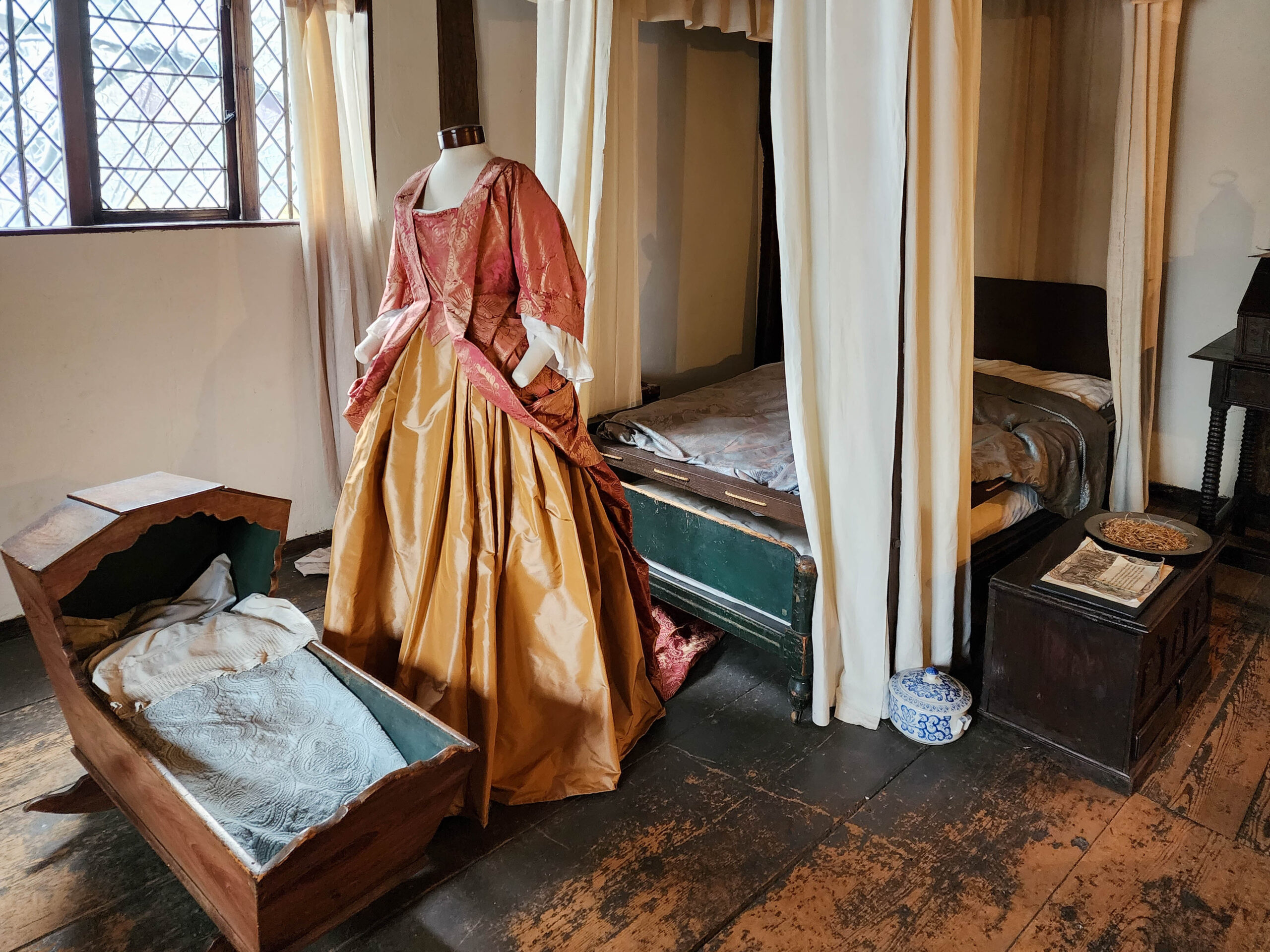 An upper chamber of the Witch House with a spinning wheel and a wooden loom beneath heavy beams