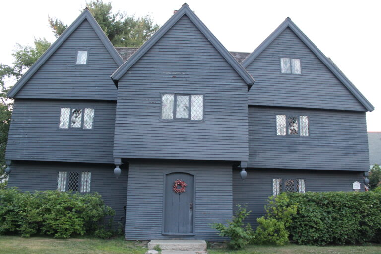 The front of the Witch House in Salem, a dark-shingled seventeenth-century house with three steep front gables and a central entry porch